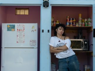 Mariabella Rivera-Todaro standing in front of the free food fridge they created in 2021. Everything in the shed is free for those in need to take.